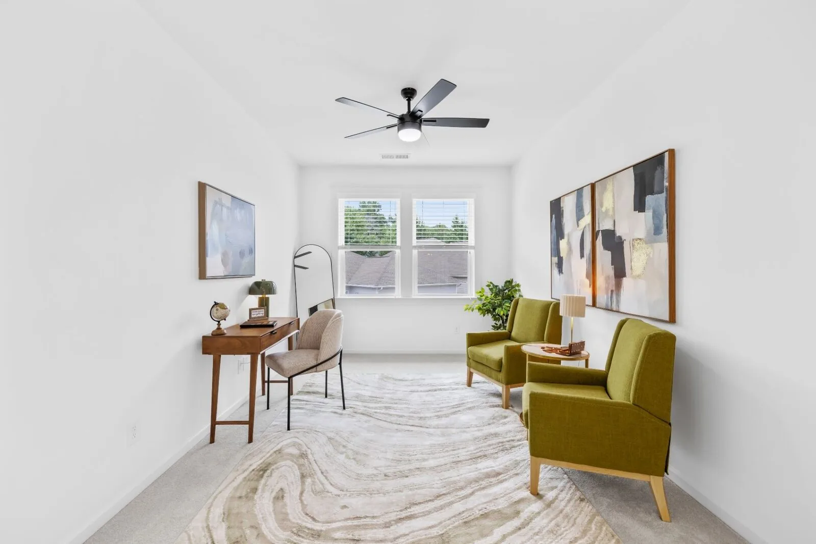 Sitting room styling with green chairs, a writing desk, artwork, and a window.