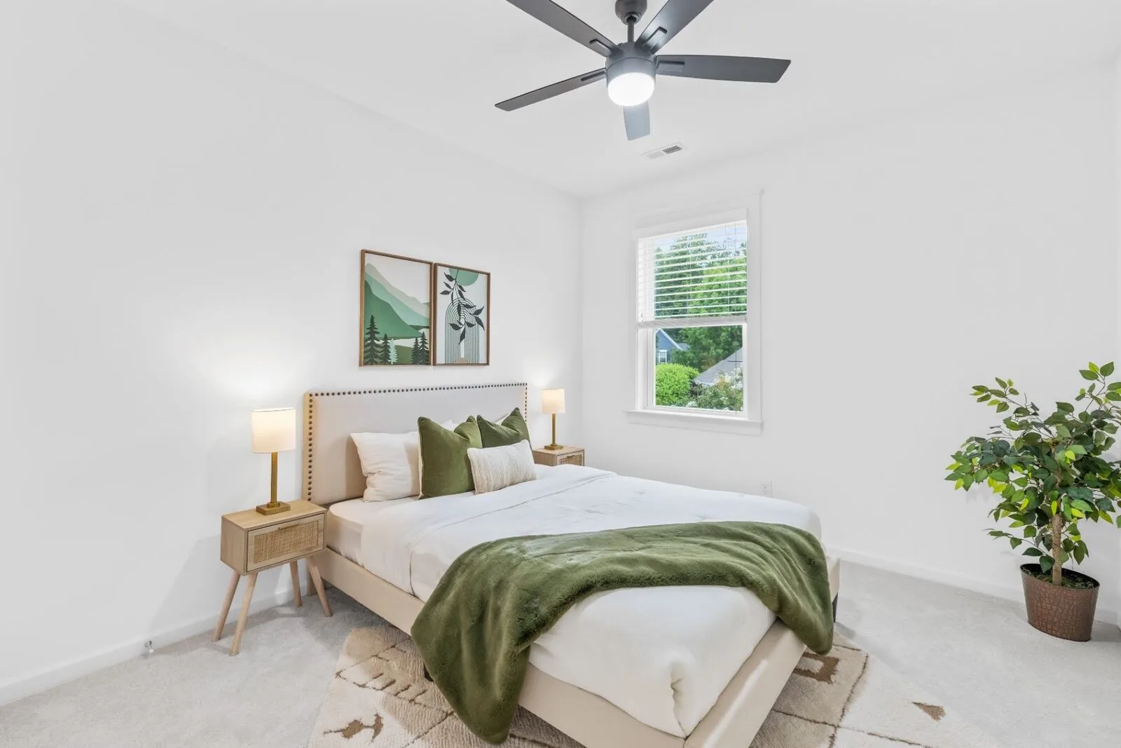 Curated bedroom interior with a light upholstered bed, a green throw, and framed artwork.