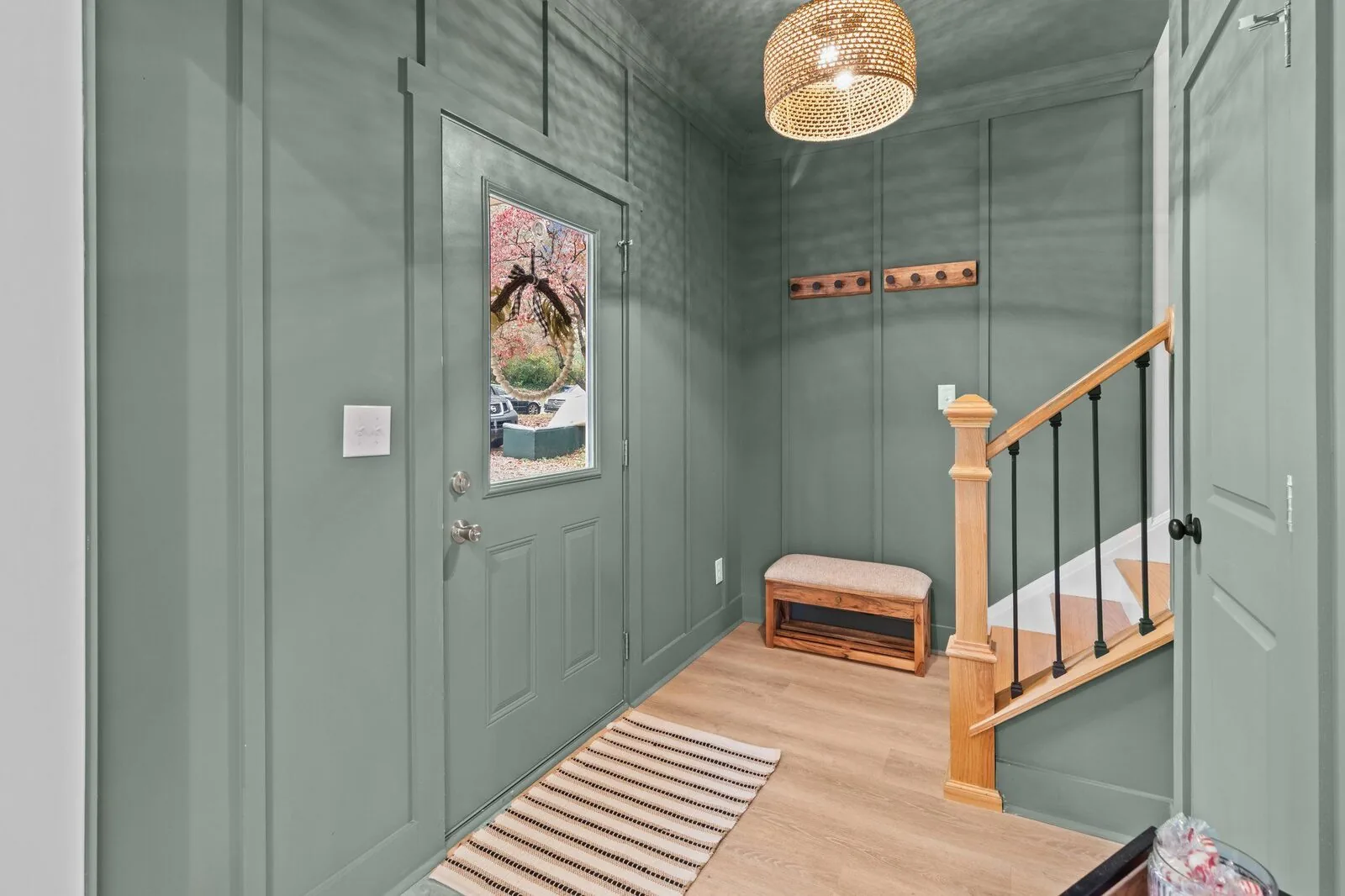 Entryway styling with paneled walls, a bench, and warm wood stairs.