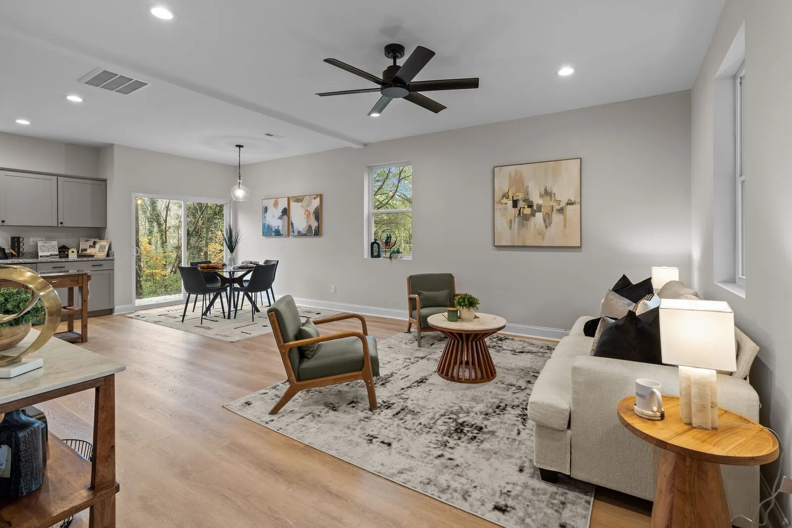 Staged living room with a sofa, lounge chairs, layered rugs, and natural light.