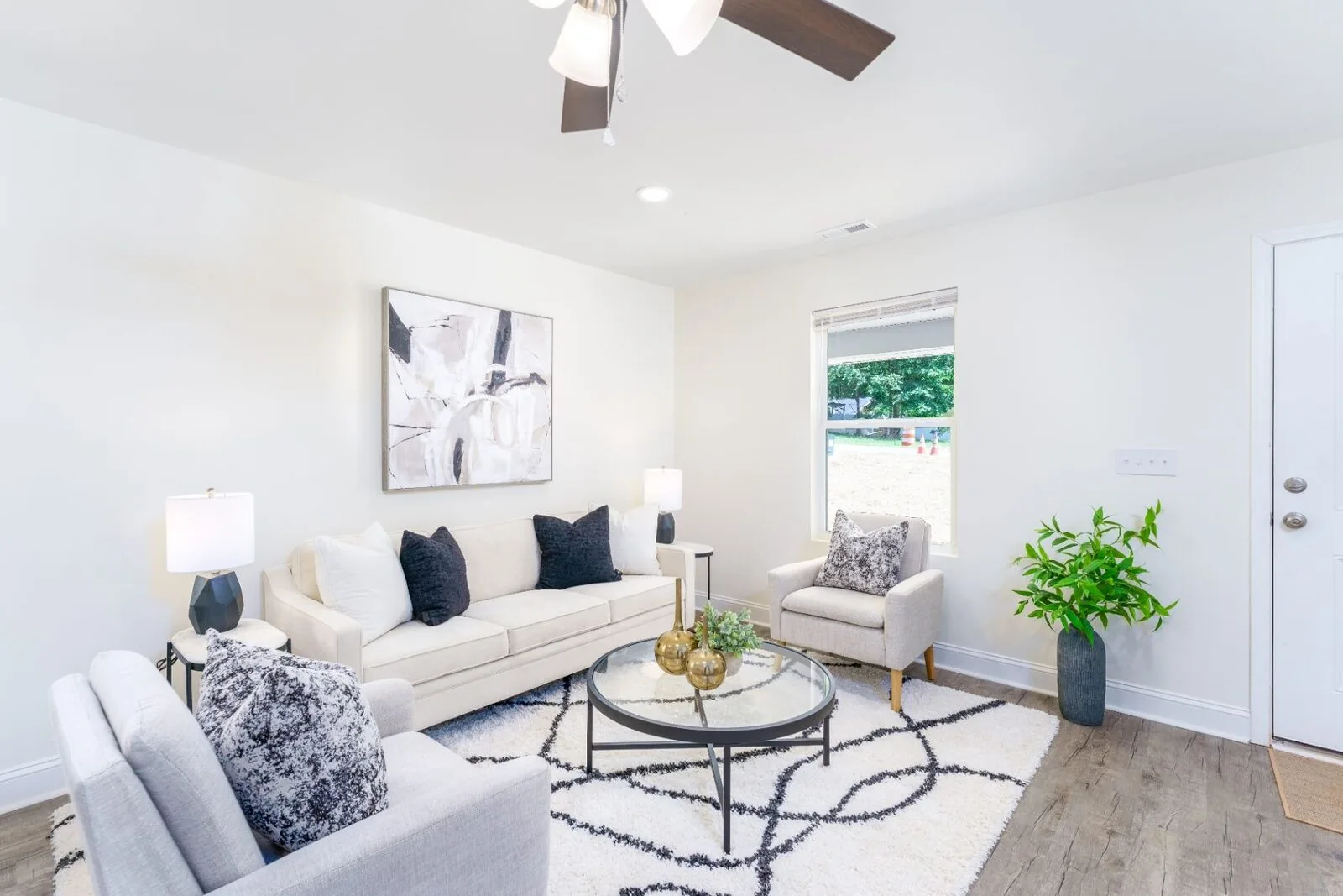 Staged living and dining interior with white seating, a round table, and a console.