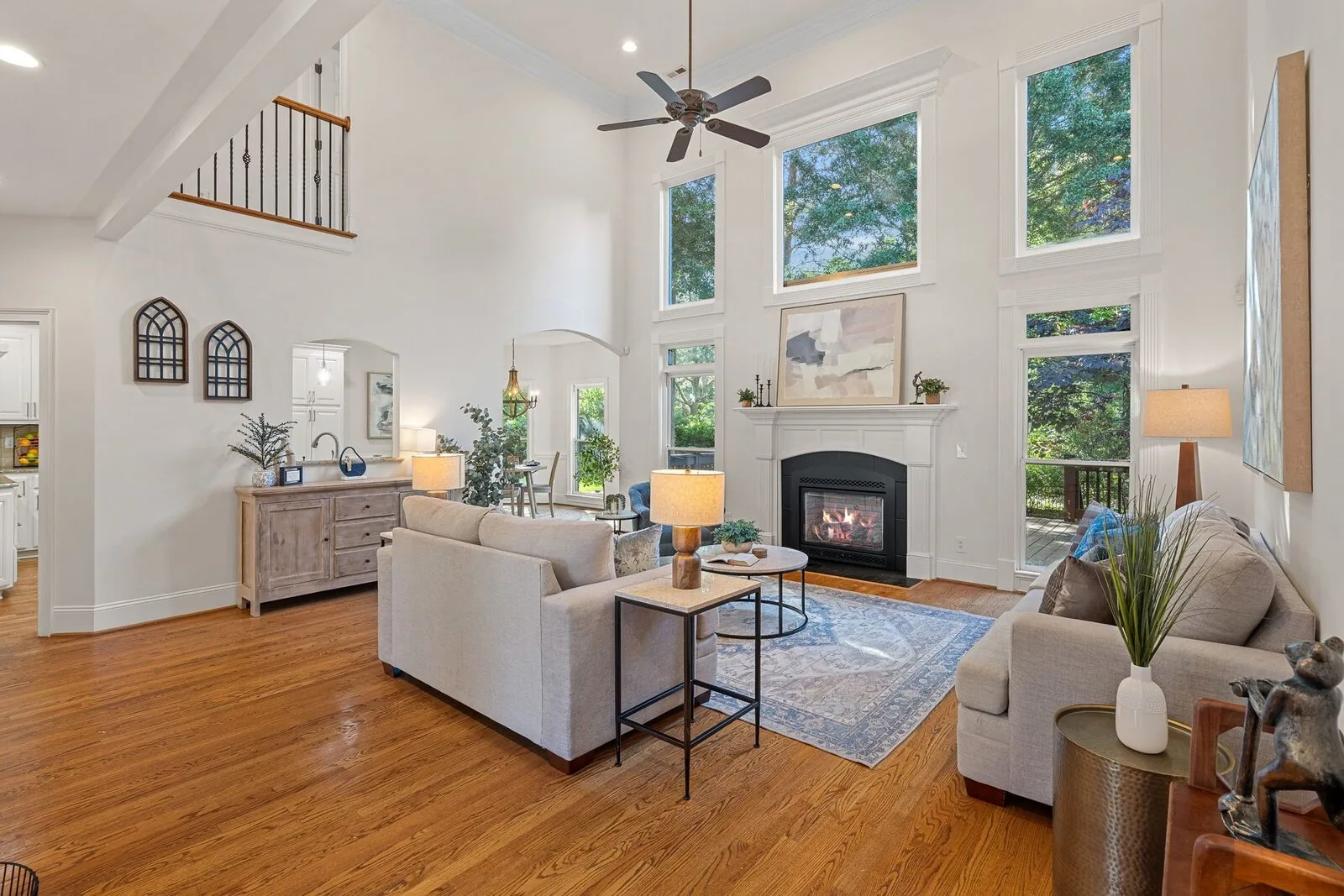 Staged living room with a fireplace, layered seating, and tall windows.
