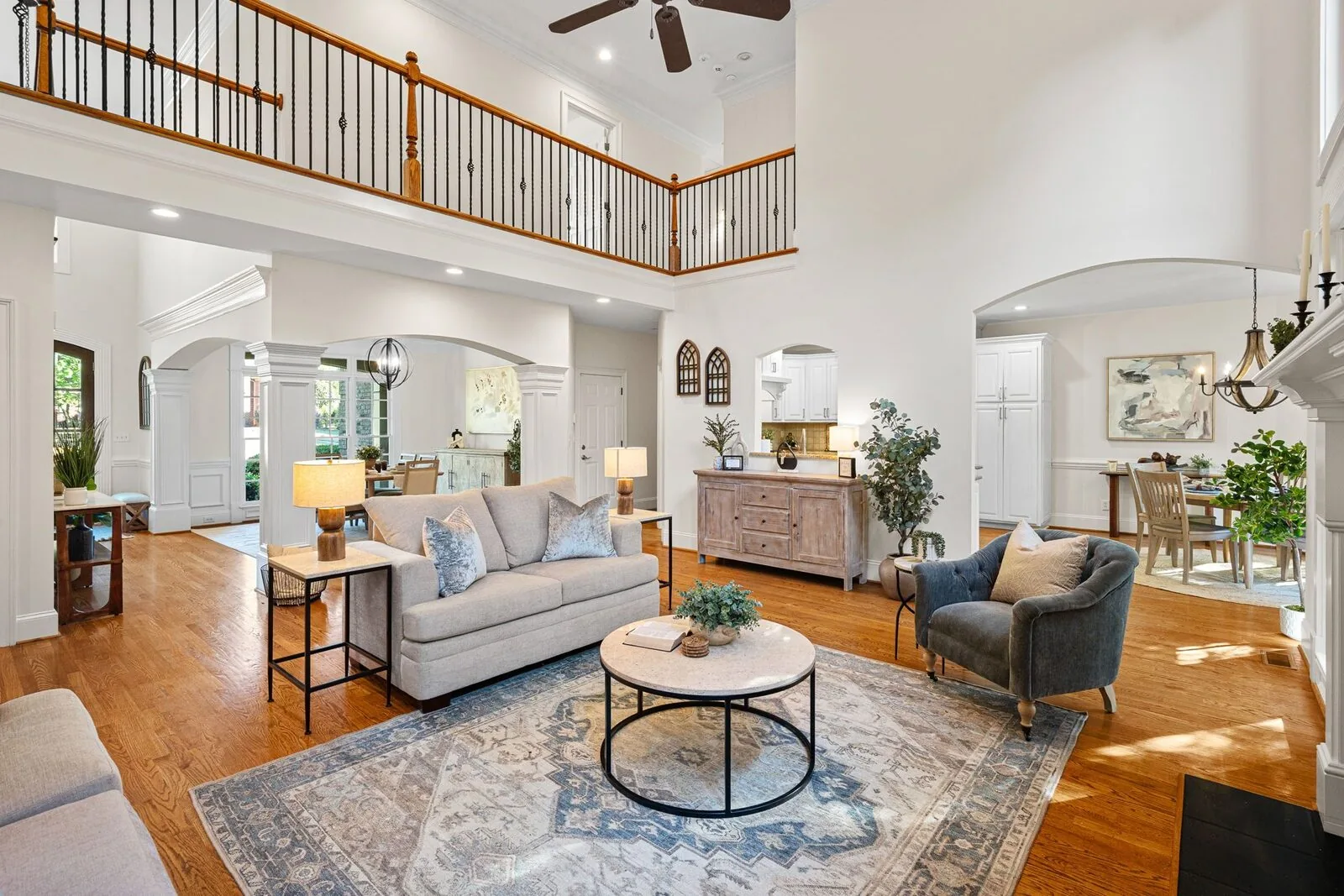 Open-concept living room with a sofa, lounge chair, dining area, and wood floors.