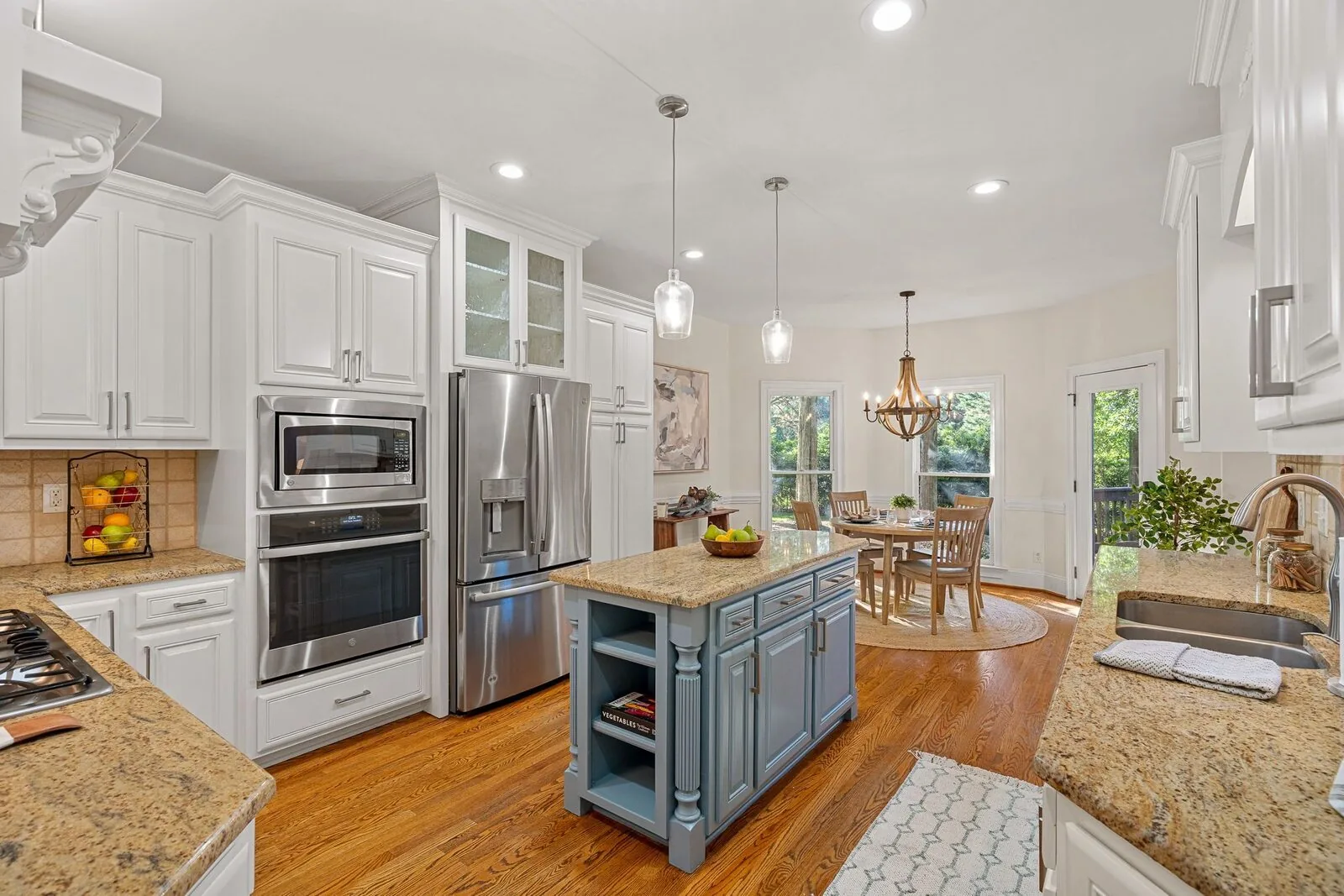 Staged kitchen with white cabinetry, a center island, and an adjoining dining area.